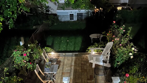 Un espace patio doté d’un sol en briques, de meubles d’extérieur blancs et d’une petite piscine.