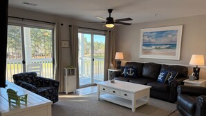 A living room with a sofa, coffee table, and a painting on the wall. - Clean and like new condo in Calabash with amazing views of the golf course. (Calabash)