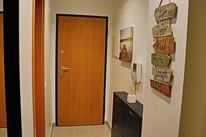 Uma porta de madeira, uma placa fixada na parede com frases motivacionais e um pequeno armário com um porta-retrato.