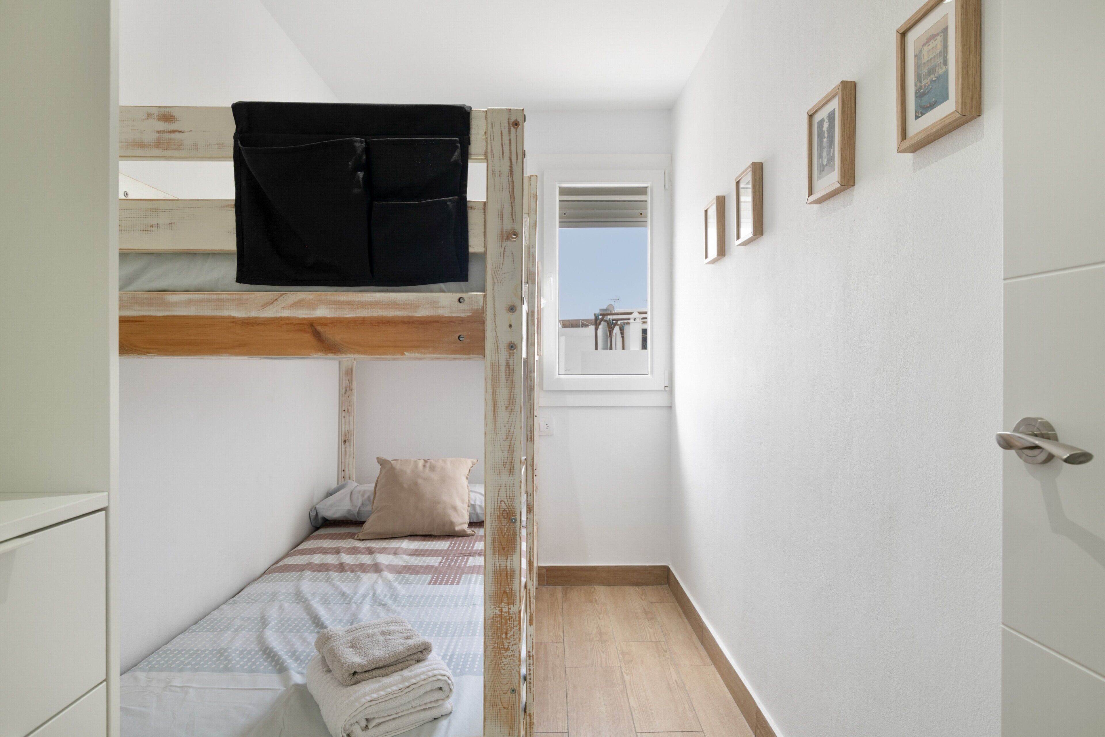 Una habitación estrecha con una litera, un ventanal pequeño y una puerta.