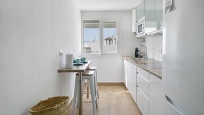 A modern kitchen with white cabinets, a wooden countertop, and a window with a view. - Apartment 'Almadraba' with Private Terrace, Wi-Fi and Air Conditioning (Barbate)