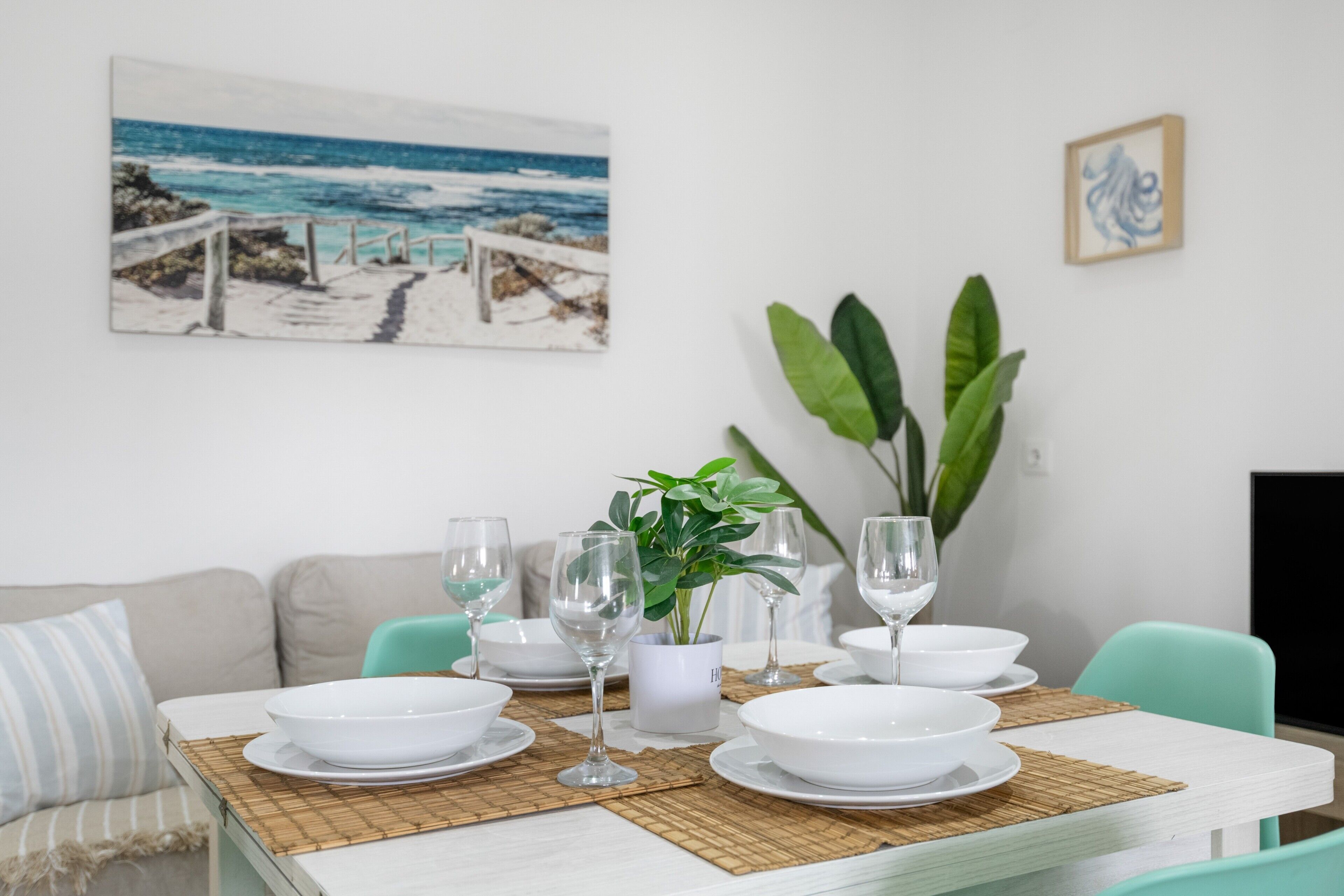 Une table à manger dressée avec de l’argenterie blanche, des verres et un arrangement floral en guise de centre de table.