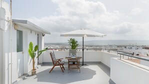 A rooftop terrace with a table set for two, a chair, a potted plant, and an umbrella. - Apartment 'Almadraba' with Private Terrace, Wi-Fi and Air Conditioning (Barbate)