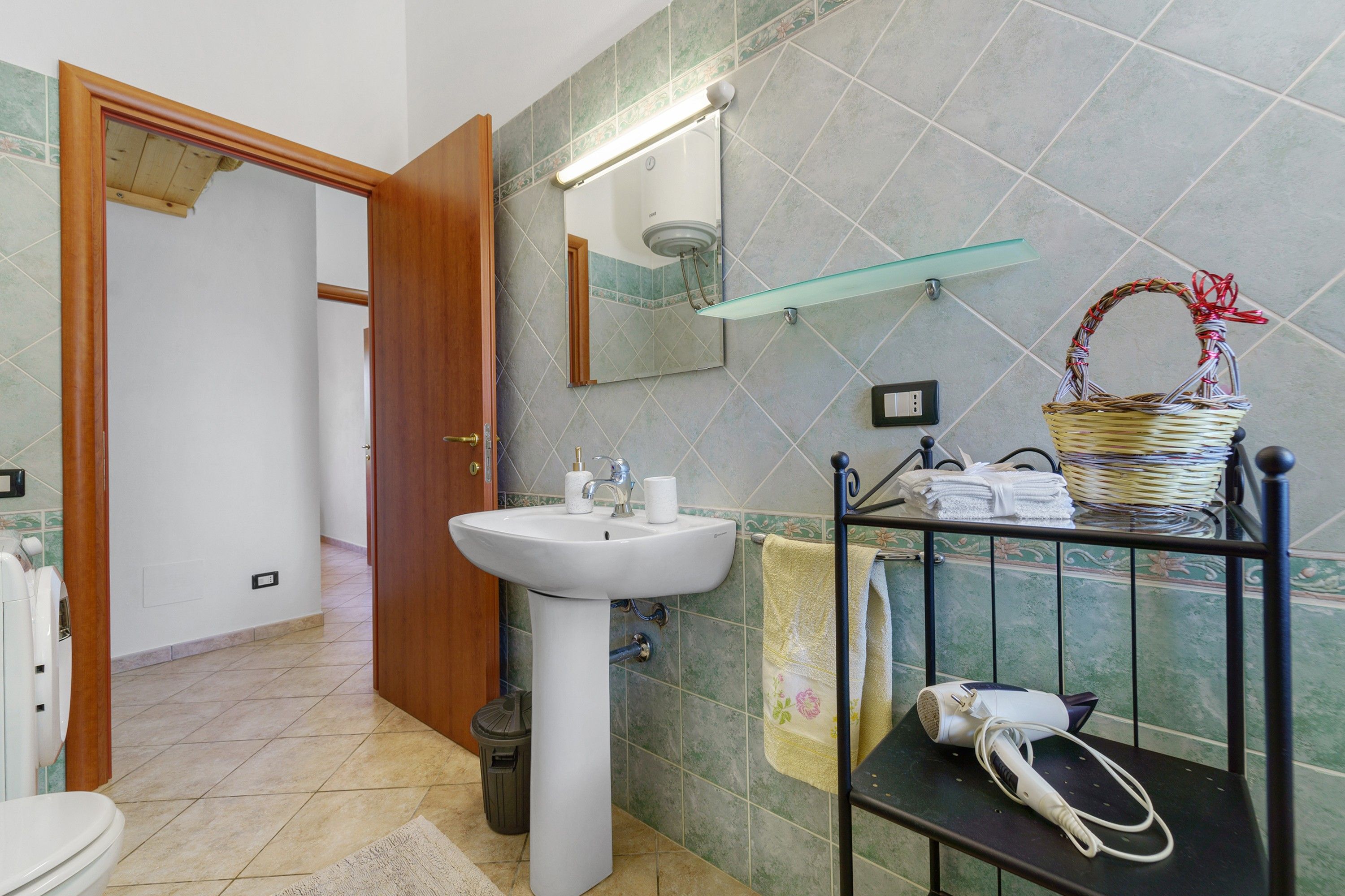 A bathroom with a sink, mirror, and towel rack.