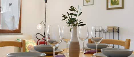 A dining table set with bowls, wine glasses, and a vase with a plant.