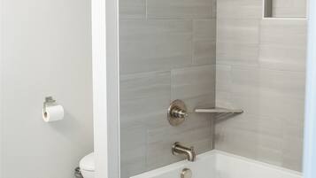 A modern bathroom with a shower, toilet, and bathtub.