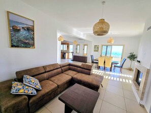 A living room with a sofa, a coffee table, and a dining area with chairs and a table. - Villa Callista Peja (Peja)