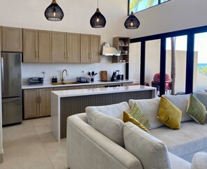 A modern kitchen with wooden cabinets, a built-in island, and pendant lighting. - Fabulous Ocean View Family Villa (Las Catalinas)