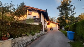 Ein zweistöckiges Haus mit Garage, Auffahrt und einer blauen Mülltonne.