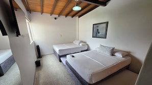 A bedroom with two beds, a wooden ceiling, a framed picture on the wall, and a window. - Casa Hotel Realeza del Estádio (Medellín)