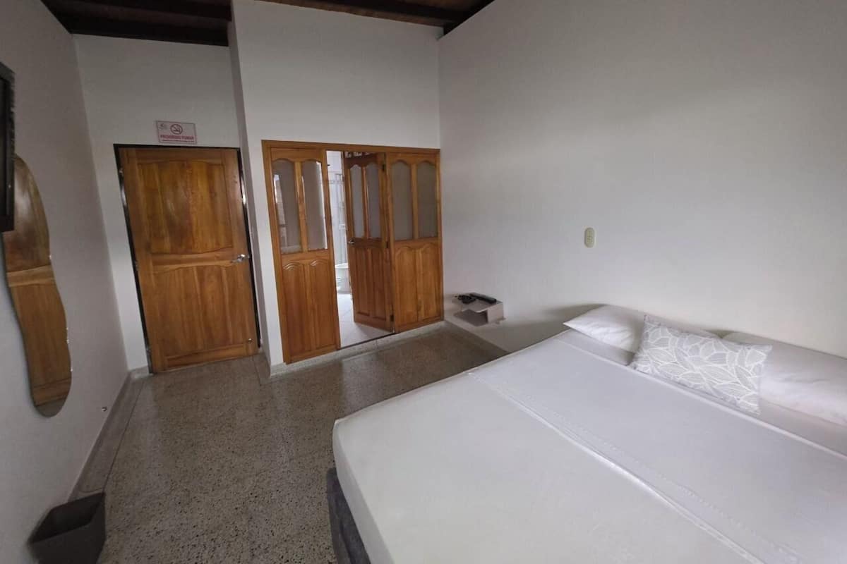 A bedroom with a bed, wooden wardrobe, and a mirror.