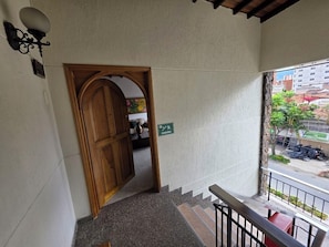 A staircase leading to a wooden door with a sign indicating 'Escalera.' - Casa Hotel Realeza del Estádio (Medellín)