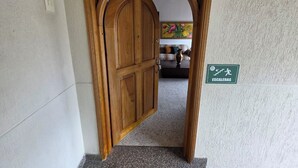 A wooden door with an archway leading to a room with a sofa and a painting. - Casa Hotel Realeza del Estádio (Medellín)