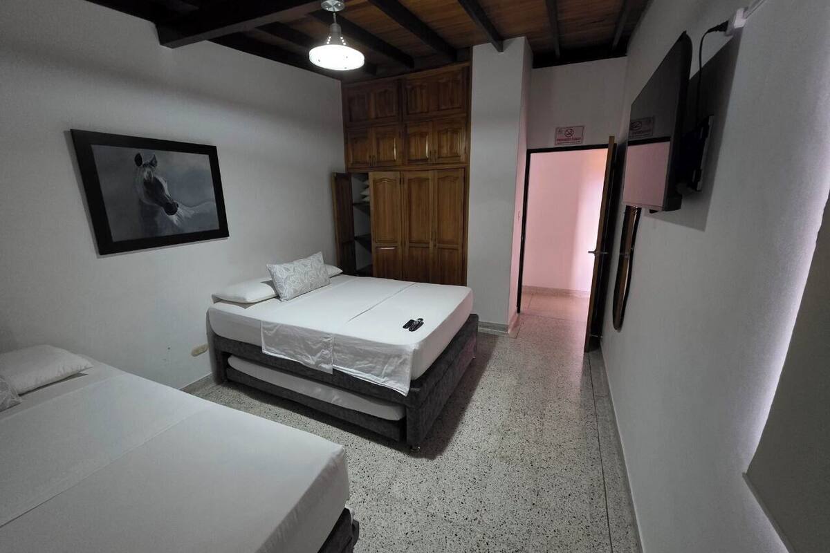 A bedroom with a bed, a wardrobe, a door, and a wall-mounted TV.