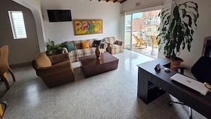 A modern living room with a sofa, armchair, coffee table, and a desk with a laptop. - Casa Hotel Realeza del Estádio (Medellín)