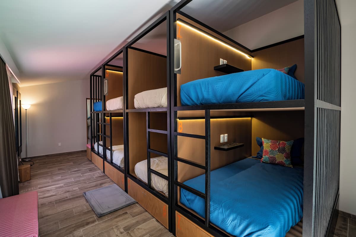Habitación de hotel compacta con literas, un escritorio pequeño y una mesita de noche.