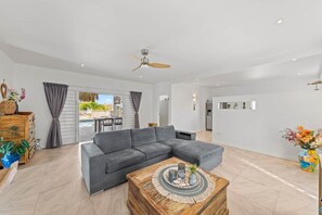 A modern living room with a grey sectional sofa, a wooden coffee table, and a ceiling fan. - Damberde House, Damascus Resort, Jan Thiel (Jan Thiel)