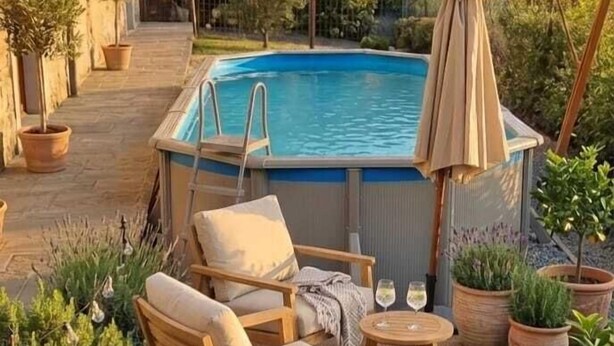 Ein Poolbereich mit Pool, Liegestühlen und einer Pergola mit Sonnenschirm.