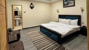 A bedroom with a bed, a ceiling fan, a nightstand, a wooden bench, and a rug.