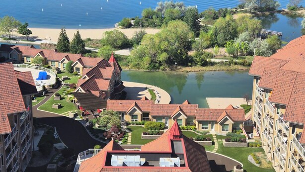 Ein Wohngebiet mit roten Ziegeldächern, einem See und einer kleinen Insel mit Bäumen.