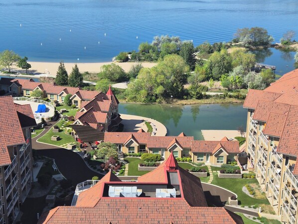 Un quartier résidentiel avec des toits recouverts de tuiles rouges, un lac et une petite île plantée d’arbres.