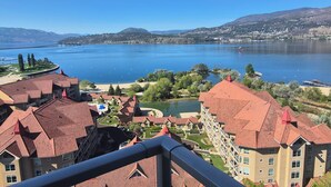 Blick auf einen See mit Gebäuden, einer Brücke und Bergen im Hintergrund.