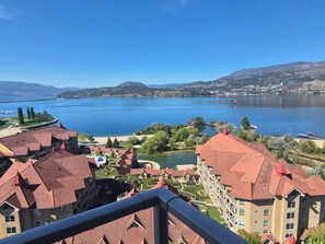 Une vue sur un lac, avec des bâtiments, un pont et des montagnes en arrière-plan.