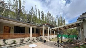 A modern building with a covered patio, a small outdoor table, and a staircase leading to an upper level. - Elegant Mountain Escape – Superior King Room in Kachura (Ponedas)