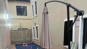 An outdoor pool area with lounge chairs, a table, and a pergola. - JOYZY HAVEN LUXURY SERVICE APARTMENT  (Ibadan)