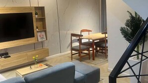 A modern living room with a TV, sofa, dining table, and chairs. - JOYZY HAVEN LUXURY SERVICE APARTMENT  (Ibadan)