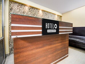A hotel reception desk with a sign indicating it is company-serviced.
