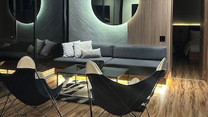 Un salon moderne avec un canapé gris foncé, deux fauteuils noirs, une table basse et deux miroirs ronds accrochés au mur.