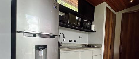 A modern kitchen with a stainless steel refrigerator, microwave, and oven, wooden flooring, and a wooden ceiling.