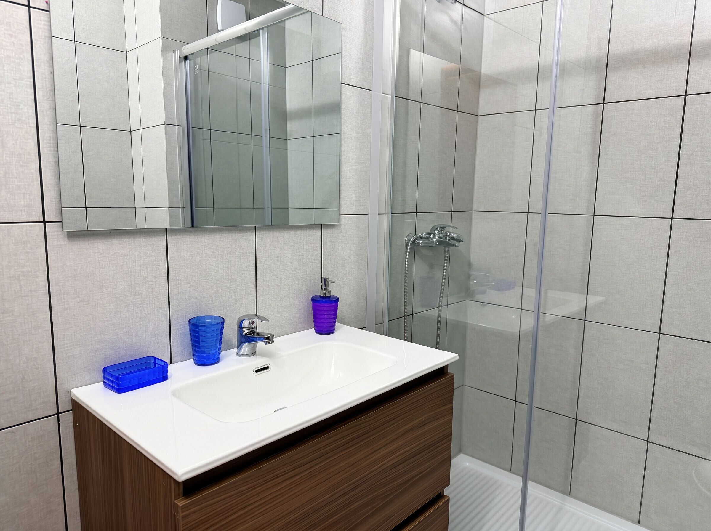 A bathroom with a white sink, a mirror, and a shower area.