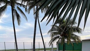 A rectangular swimming pool with clear water reflecting palm trees, surrounded by a white fence, and a view of the ocean in the background. - Enjoyable 4-bedroom country house with AC in Playa El Amatal (playa el amatal)