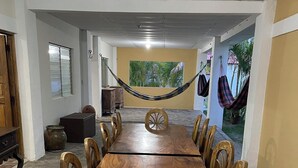A long wooden dining table with chairs, a hammock, and a view of palm trees. - Enjoyable 4-bedroom country house with AC in Playa El Amatal (playa el amatal)