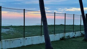 A chain-link fence with trees in the foreground and a sunset in the background. - Enjoyable 4-bedroom country house with AC in Playa El Amatal (playa el amatal)