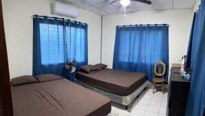 A room with two beds, a ceiling fan, an air conditioner, a wooden chair, and a desk with a computer. - Enjoyable 4-bedroom country house with AC in Playa El Amatal (playa el amatal)