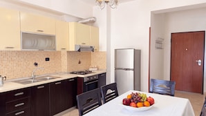 A modern kitchen with a dining area, including a stainless steel refrigerator, a gas stove, and a chandelier. - Holiday Home by the Beach Durres 117 (Durres)