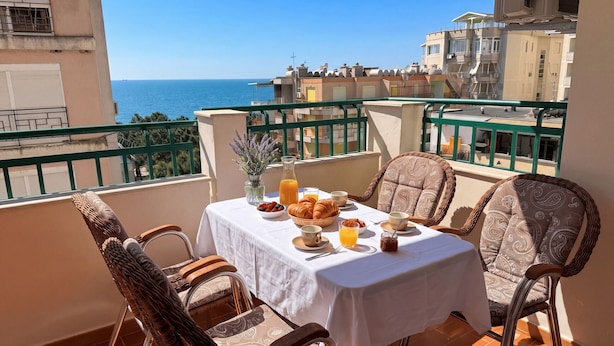 A balcony with a table set for breakfast, wicker chairs, and a view of the sea. - Holiday Home by the Beach Durres 117 (Durres)
