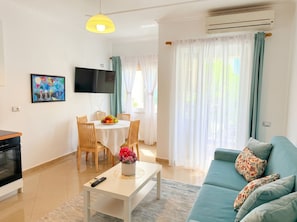 A living room with a sofa, TV, dining table with chairs, and a kitchen area. - Cozy Holiday Apartment by the Beach 106 (Durres)