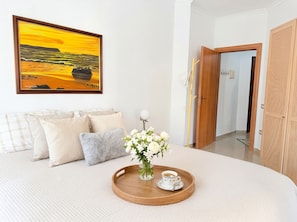 A bedroom with a bed, pillows, a tray with flowers and a cup, a painting, and a door. - Cozy Holiday Apartment by the Beach 106 (Durres)