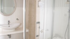 Une salle de bain avec une douche à parois de verre, un lavabo et un miroir.