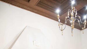 Une pièce avec une cheminée, une table ronde, deux chaises, un téléviseur fixé au mur et un lit recouvert d’une couverture bleue.
