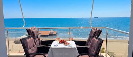 A balcony with two chairs and a table, overlooking the sea.