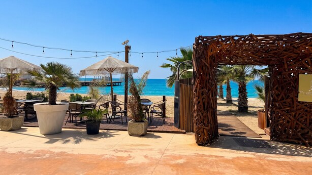 A beachside patio with outdoor seating, umbrellas, and a wooden pergola. - Beachfront- Sea View Holiday Home 105 (Durres)