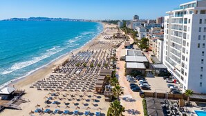 A beachside hotel with rows of sun loungers, a pool, and a view of the ocean. - Beachfront- Sea View Holiday Home 105 (Durres)