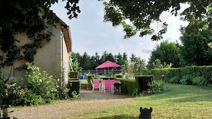 A garden with a statue, a red umbrella, and a paved area with chairs. - Nature lovers Close to the BEAUVAL zoo and the Loire castles (CHATILLON SUR INDRE)