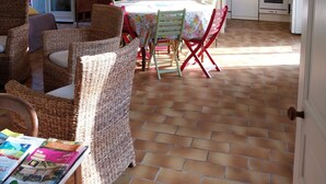 A spacious dining area with wicker chairs and a table, a kitchen with white appliances, and a tiled floor. - Nature lovers Close to the BEAUVAL zoo and the Loire castles (CHATILLON SUR INDRE)