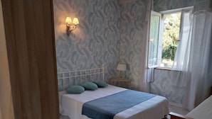A bedroom with a bed, a nightstand, a wall-mounted lamp, and a window with curtains. - Nature lovers Close to the BEAUVAL zoo and the Loire castles (CHATILLON SUR INDRE)